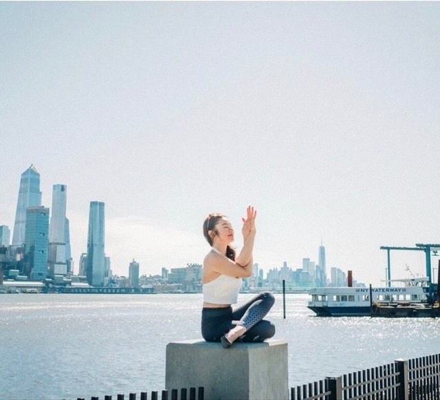 海を背にヨガをする女性